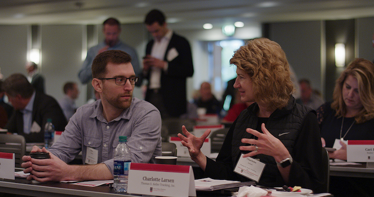 Professionals at a conference converse in an animated fashion with hand gestures