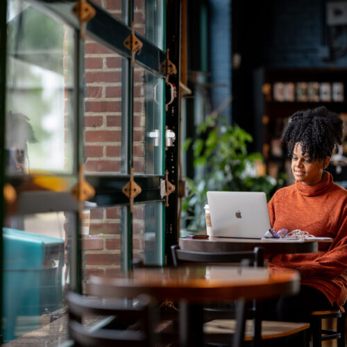 Woman in an orange shirt working on a laptop