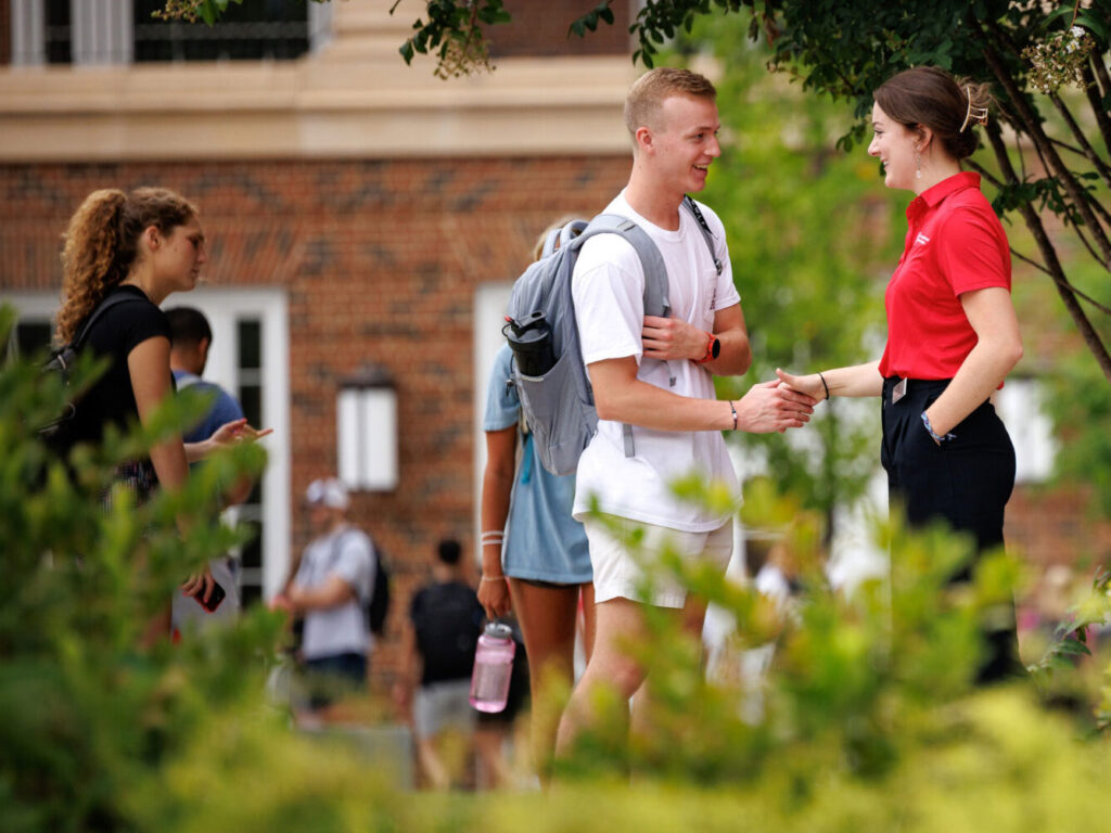 20220817_firstday_009-1-crop-sm students greeting eachother shaking hands outdoors