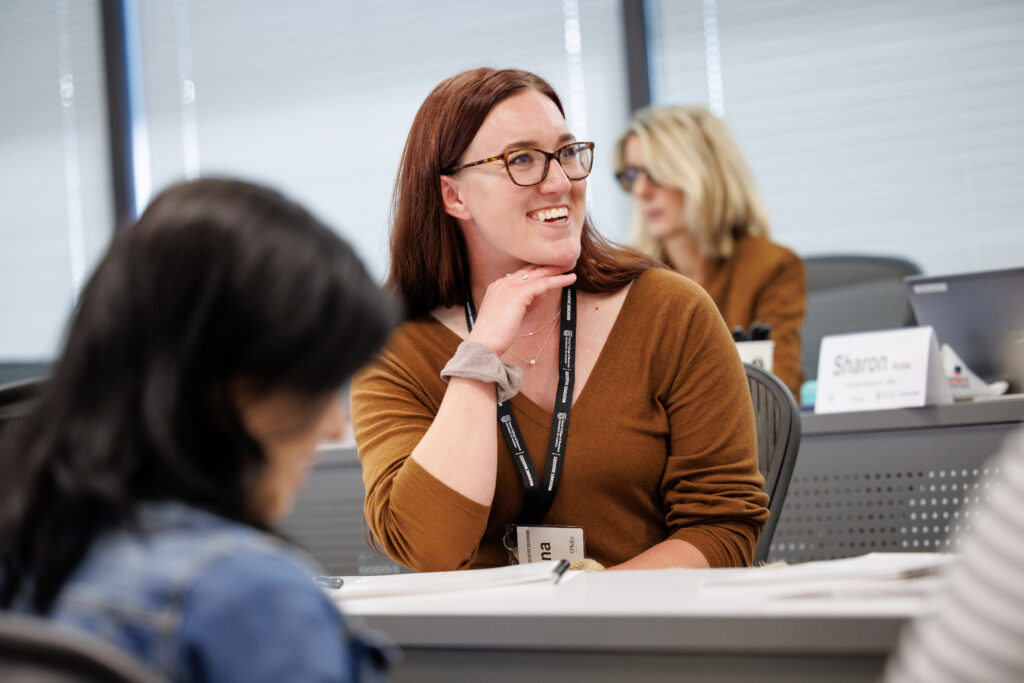 A woman smiles at in a classroom while attending a Terry College of Business Executive Education event