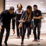 two graduate students dancing in front of other students in classroom