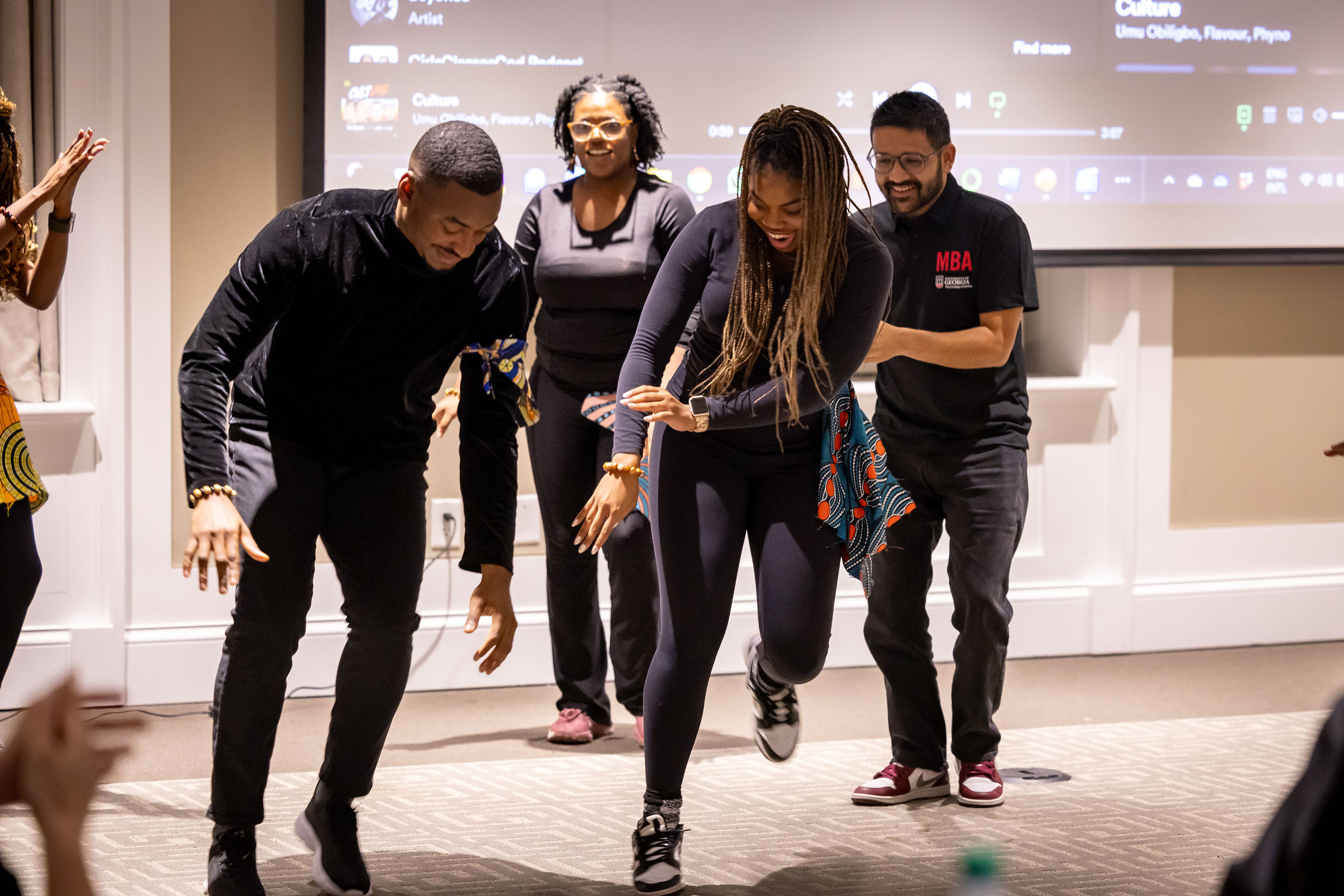 two graduate students dancing in front of other students in classroom