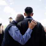 candid shot of father hugging son from back after convocation ceremony