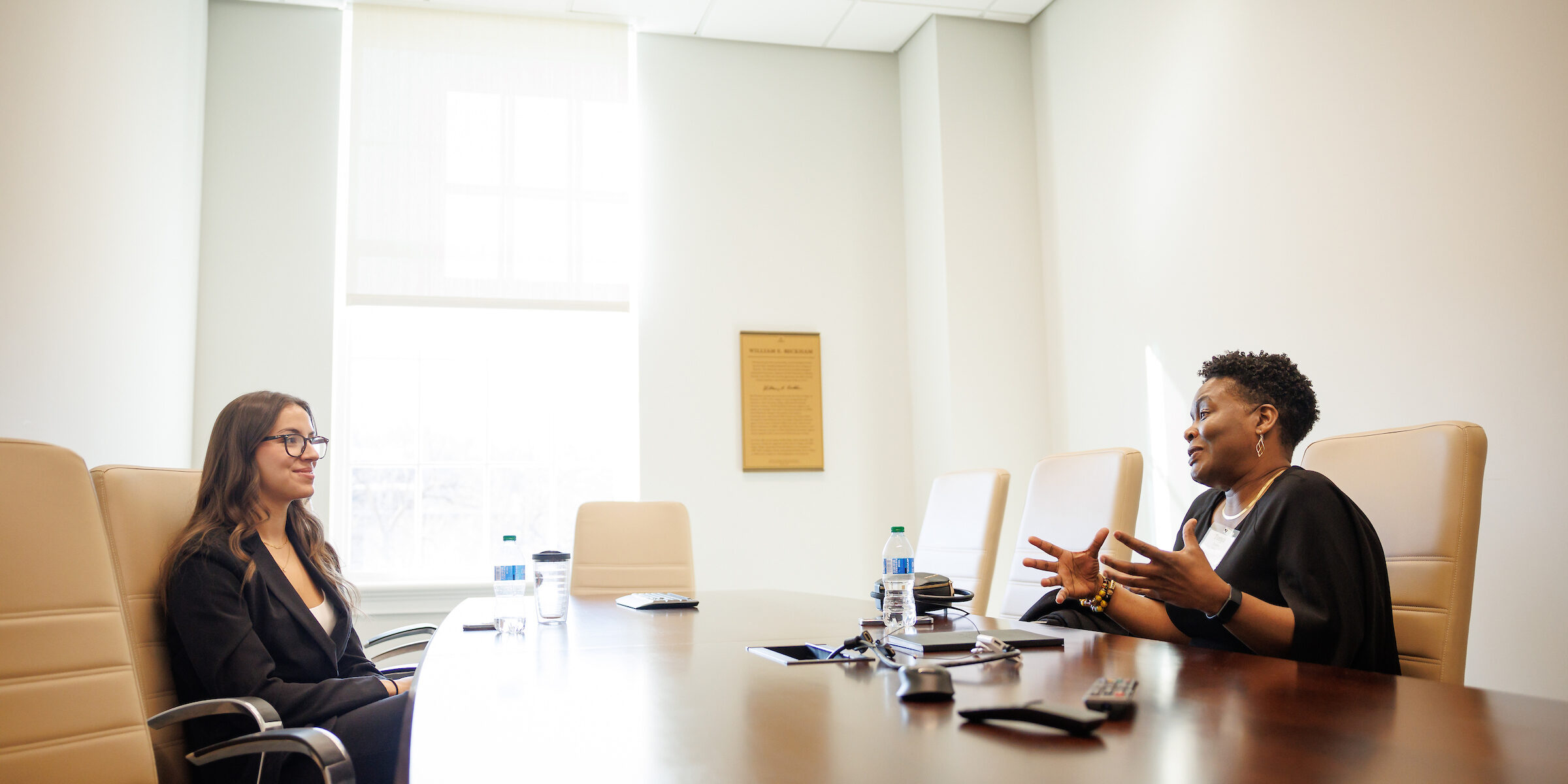 Two professional women speaking to each other in a conference room