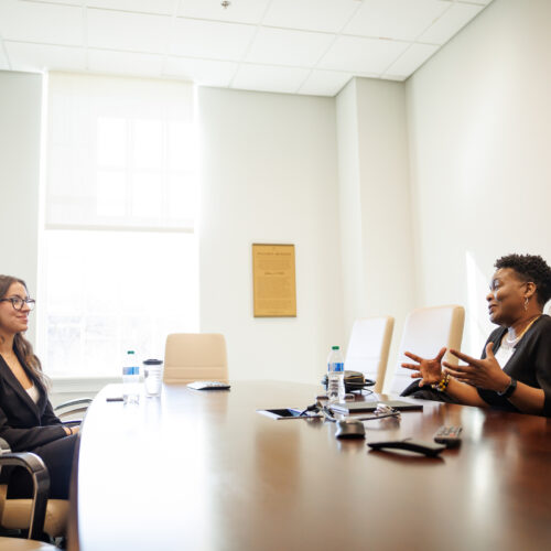 Two professional women speaking to each other in a conference room
