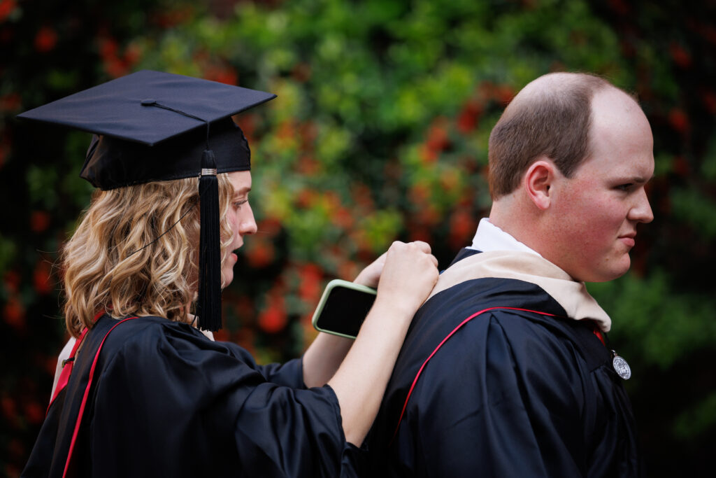 graduate assisting friend with Master's degree hood