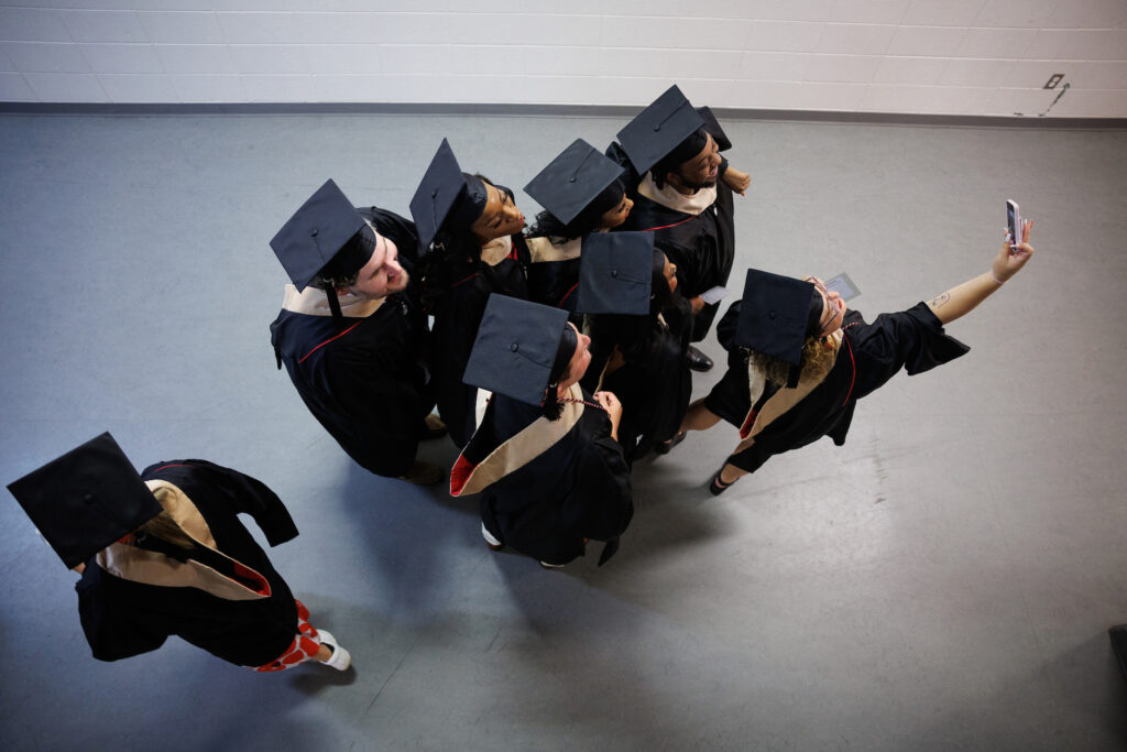 overhead of graduates taking selfie in hallway