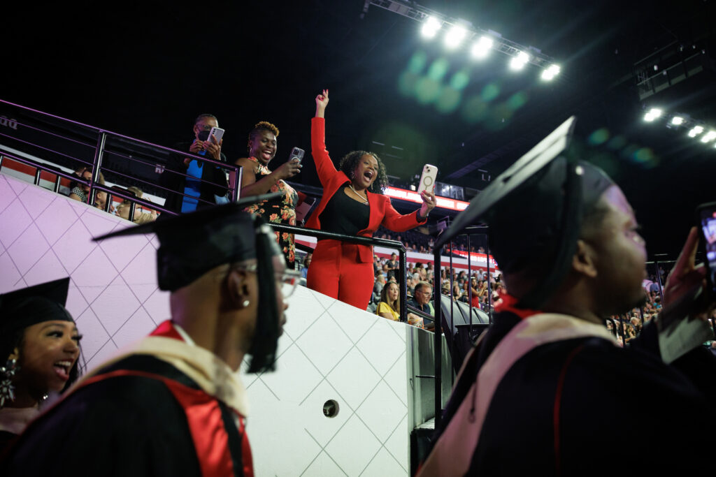 woman cheering on graduates as they walk by