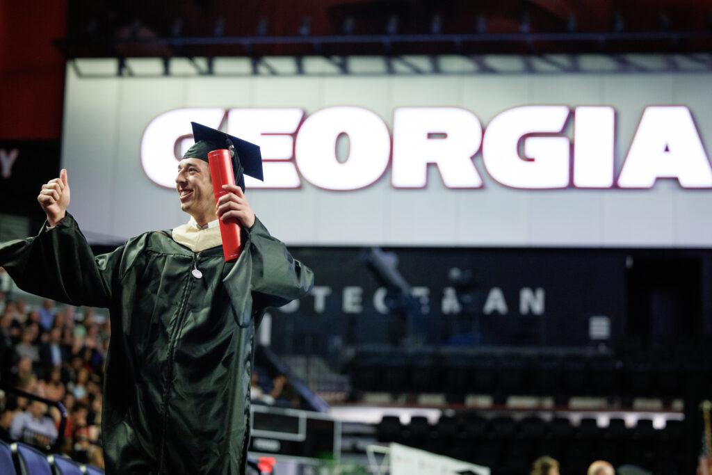graduate gives thumbs up from stage