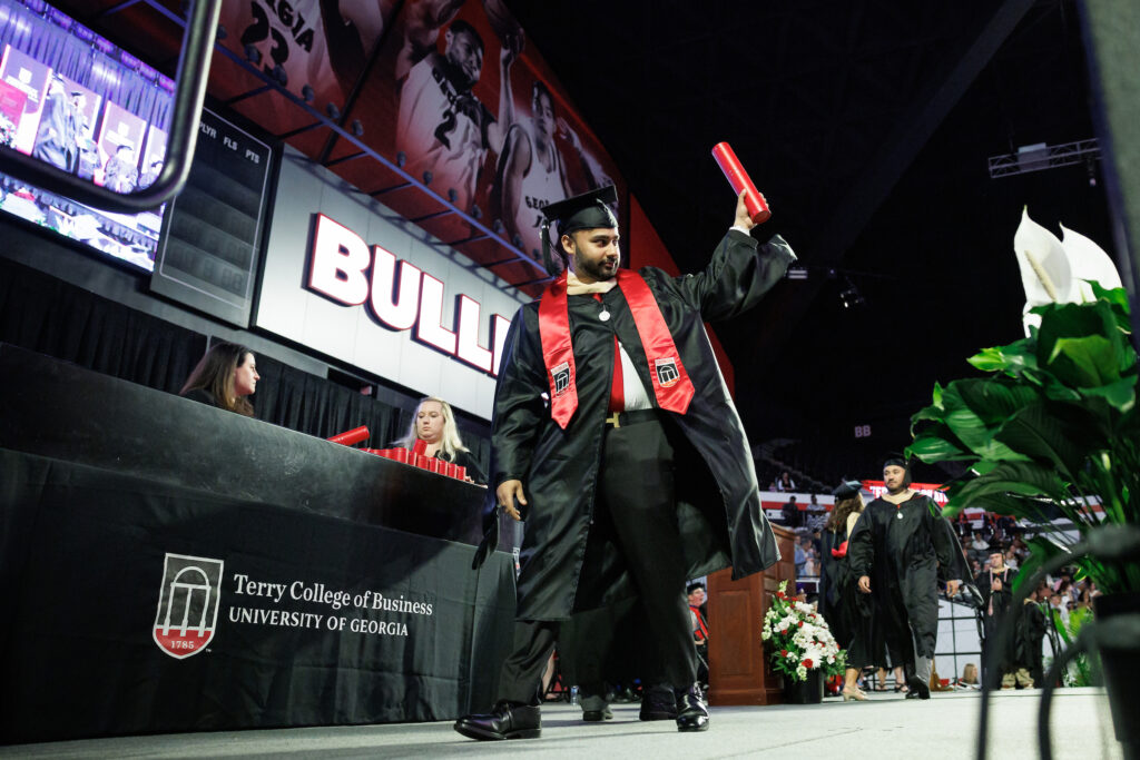 graduate raises diploma tube on stage