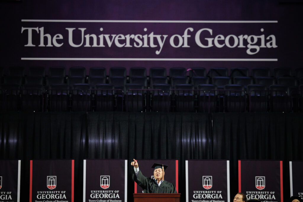 convocation speaker points to crowd under University of Georgia banner