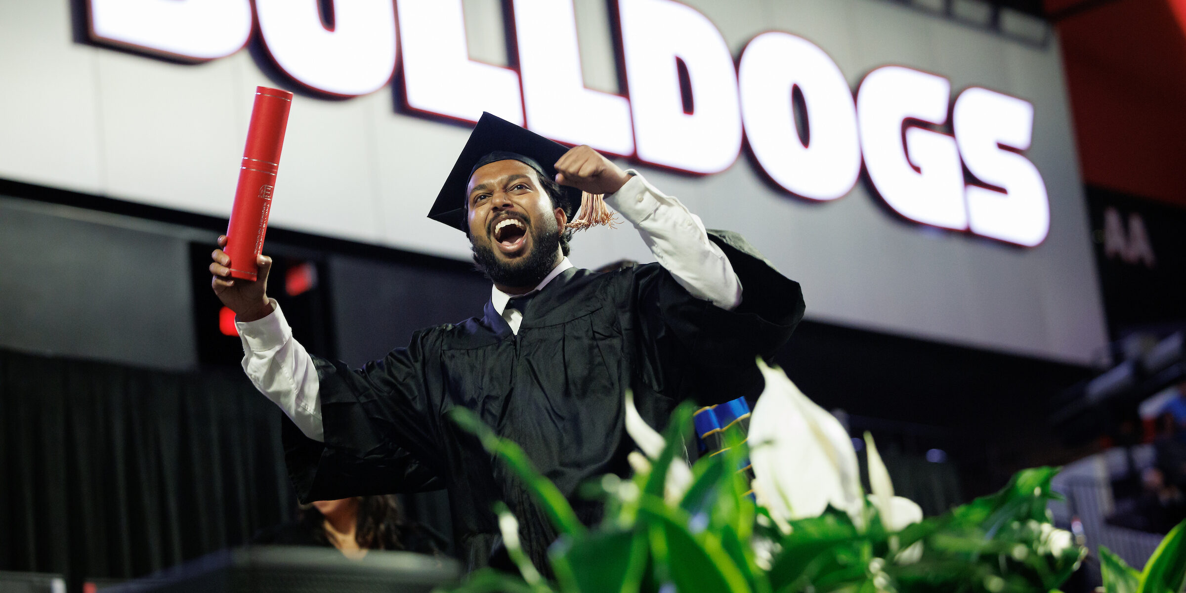 male graduate celebrates on stage after being recognized