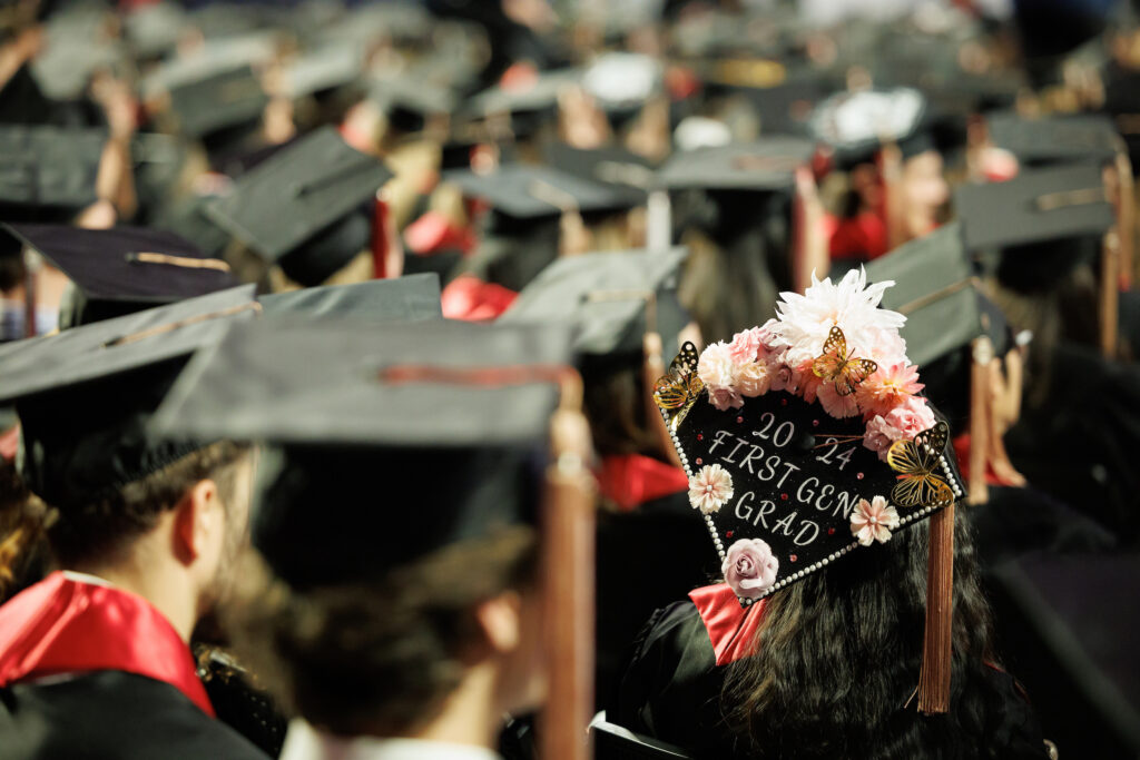 backs of graduates' heads with one cap reading "2024 first gen grad"