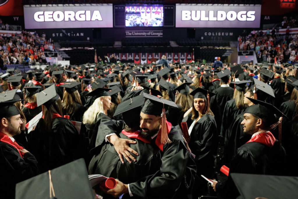 two graduates share a celebratory hug at convocation