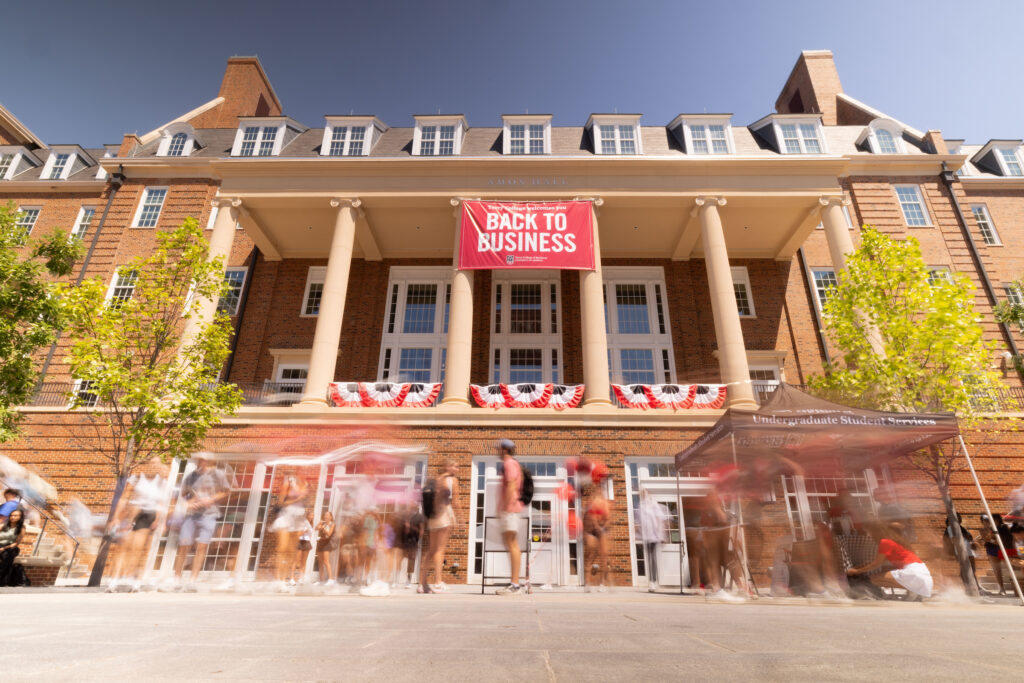 A crowd of people gather in Coca-Cola Plaza in front of a large "Back to Business' sign hung off of Amos Hall.