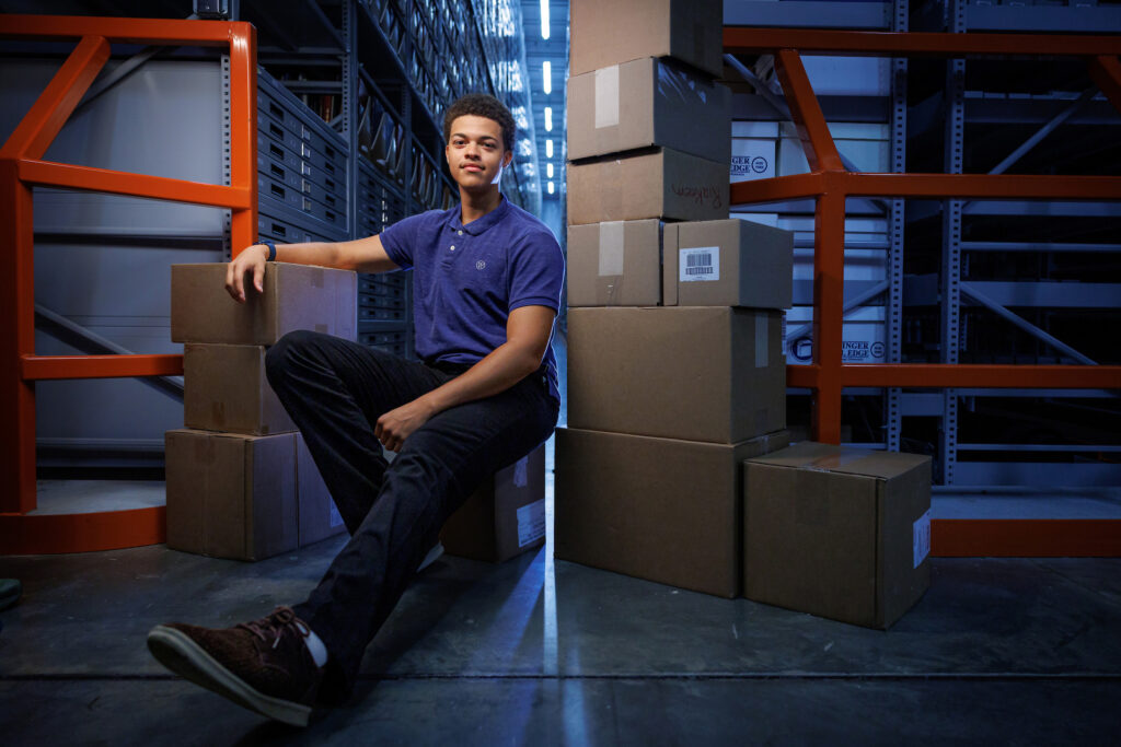Julian Squires poses with boxes in a warehouse.