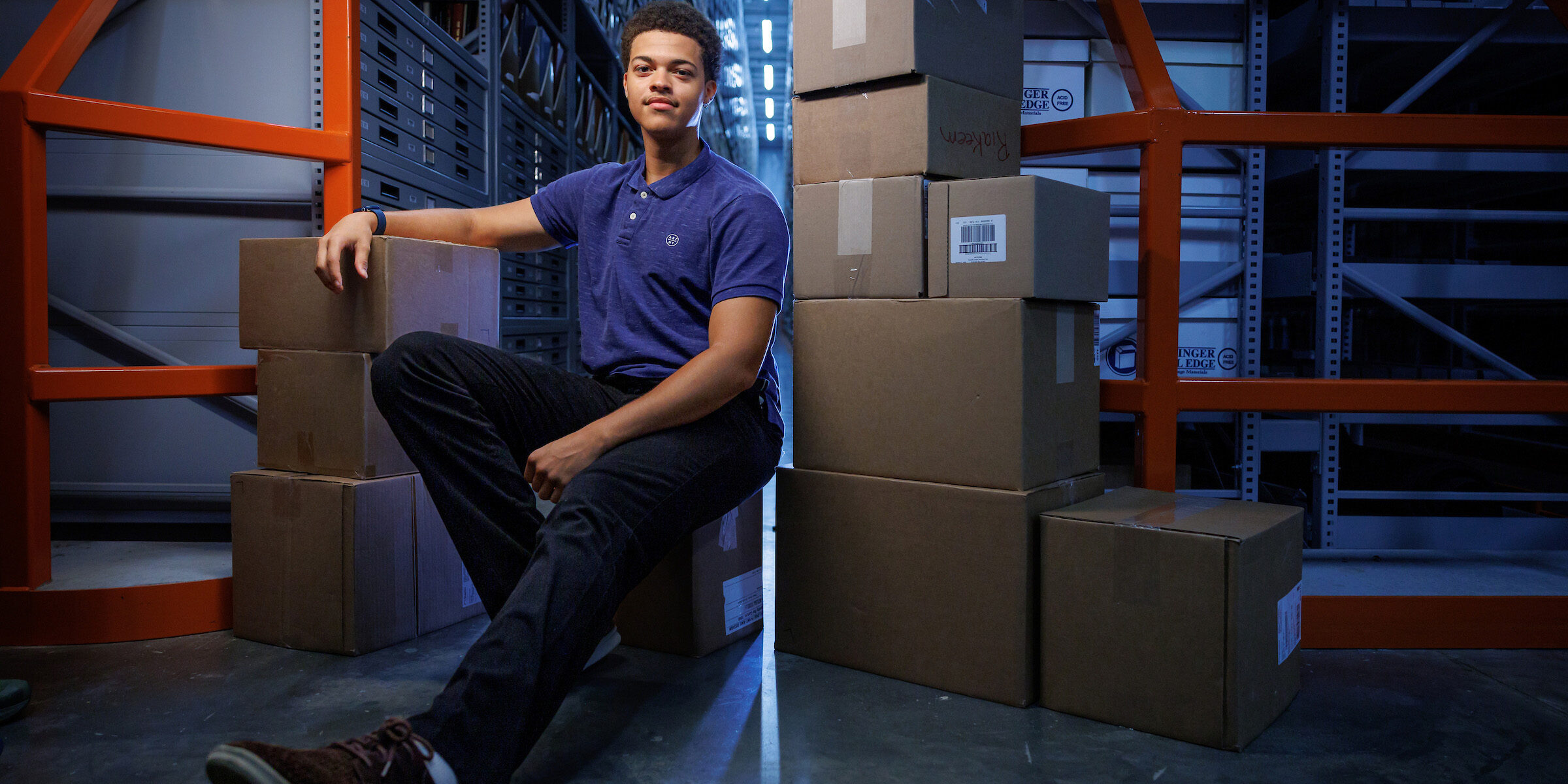Julian Squires poses with boxes in a warehouse.