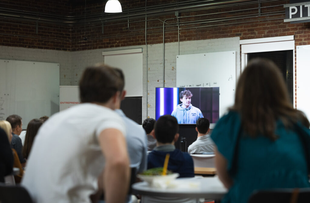 A crowd watches UGA alum Matt Tesvich on TV at his watch party for the premier of the show "Buy it Now!"