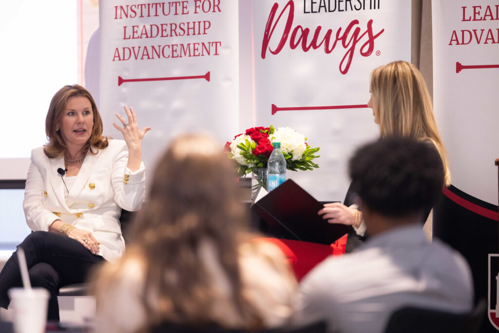 Lauren Koontz speaks with ILA student Charlotte Ferrell in front of ILA banners