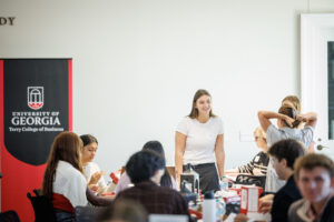 A woman in a white shirt gives a presentation in front of a sitting crowd