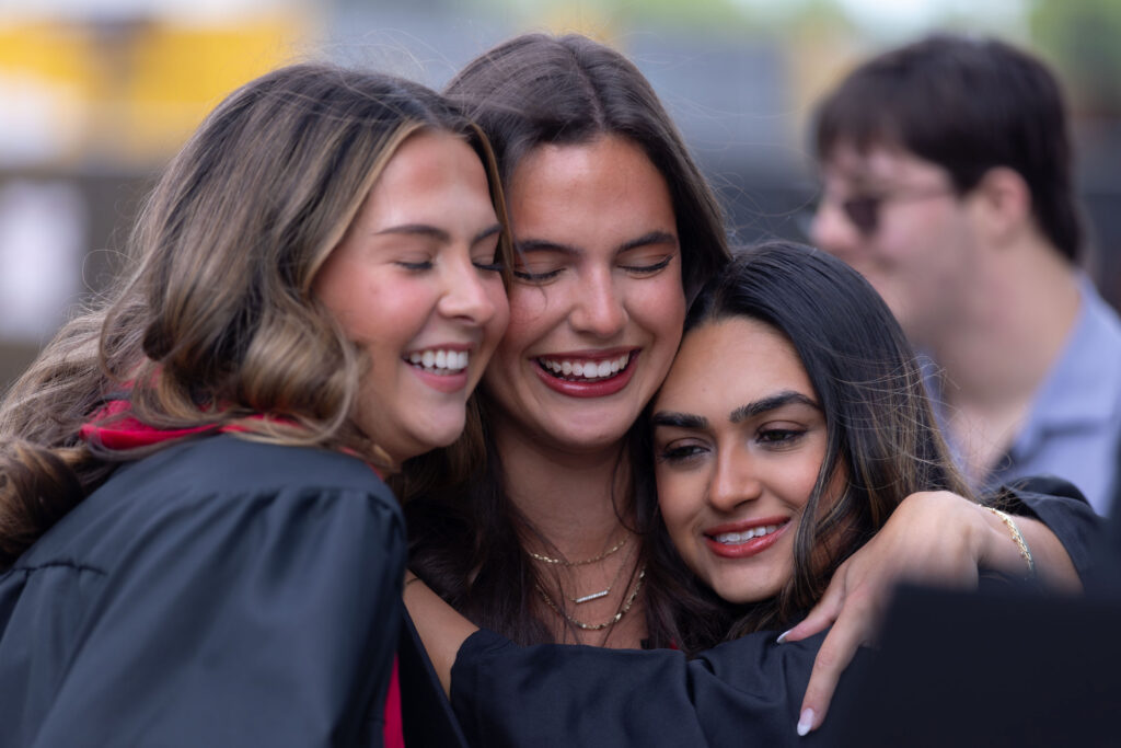 2026.05.08_rh_Undergrad_Convocation_027 Three female graduates share a hug outside of Stegeman Coliseum after Terry College Undergraduate Convocation on May 8.