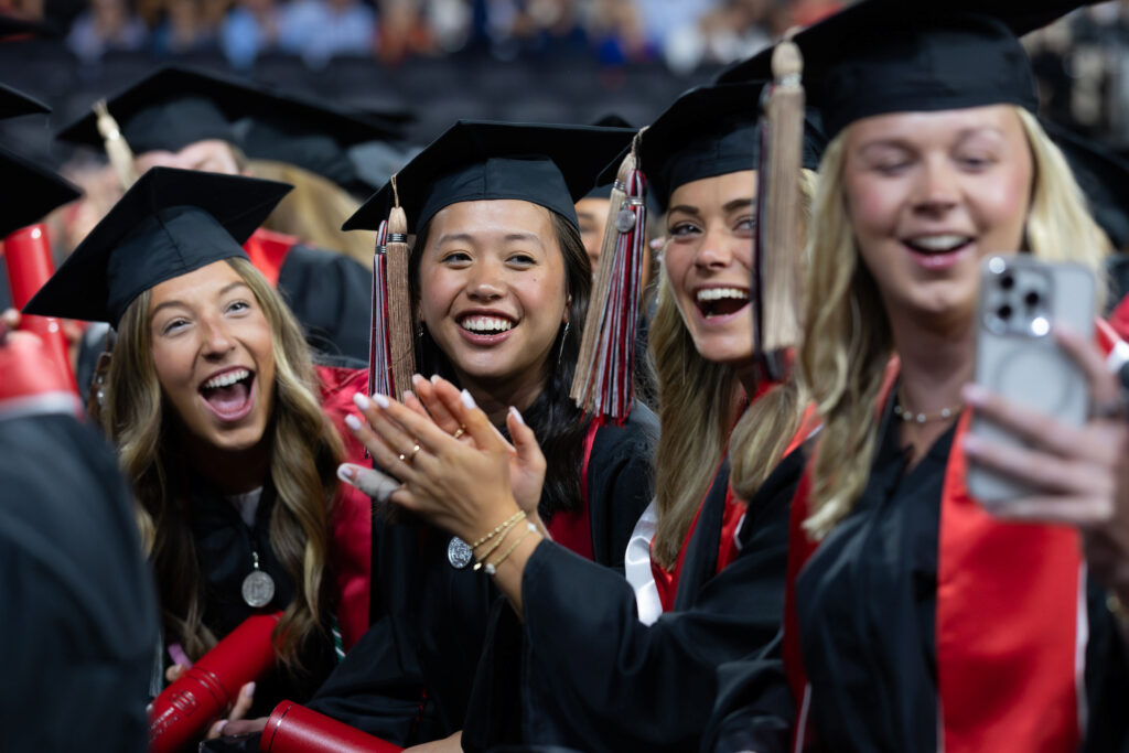 2026.05.08_rh_Undergrad_Convocation_042 A group of female graduates share pose for a whole-row selfie on the floor of Stegeman Coliseum after Terry College Undergraduate Convocation on May 8.