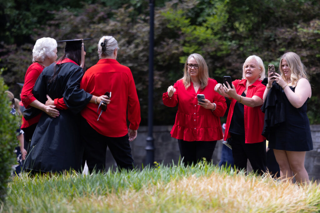 2026.05.08_rh_Undergrad_Convocation_047 A family poses with their graduating student while three female family members take photos outside of Stegeman Coliseum after Terry College Undergraduate Convocation on May 8.
