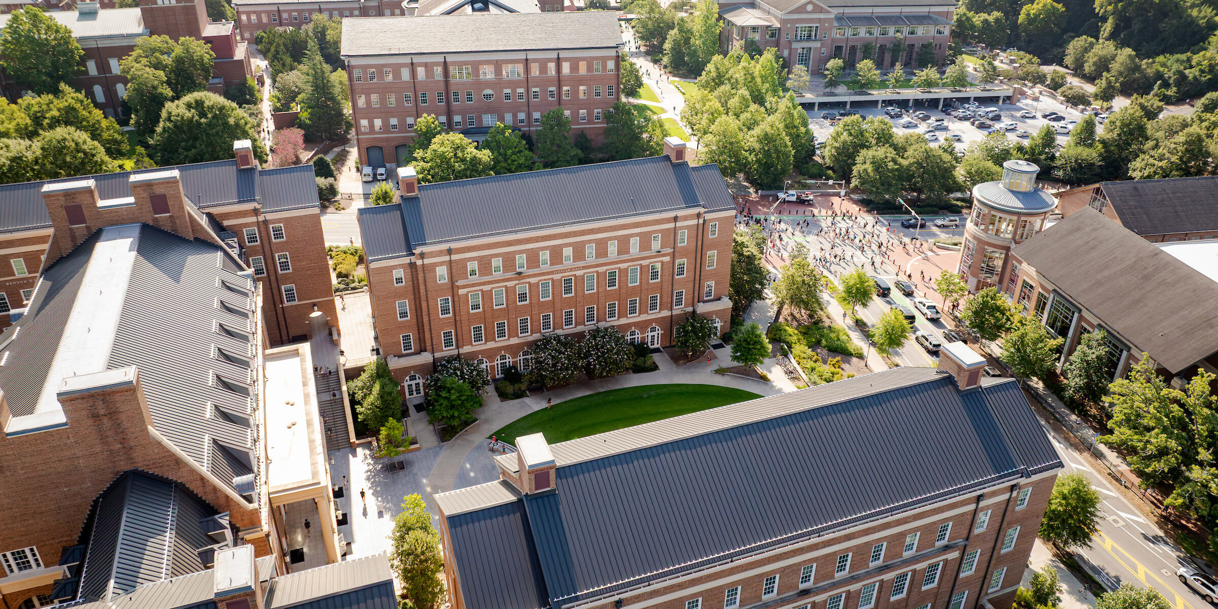 An aerial view of a university campus featuring brick buildings, green lawns, and a large stadium surrounded by trees.