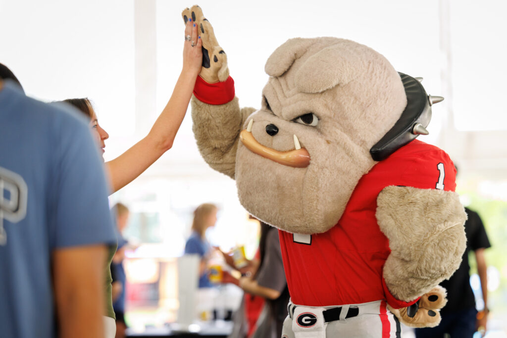 20260825_b2b_bp_07 A bulldog mascot in a red jersey gives a high-five to a person at an event.