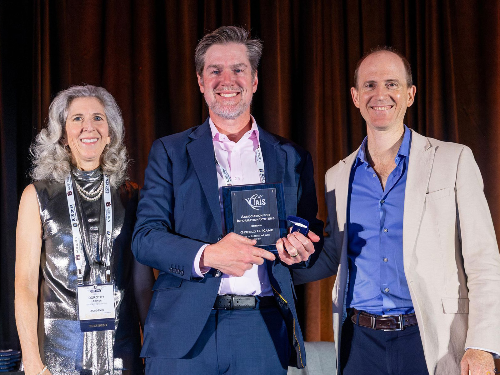 Dorothy Leidner, AIS President, and (far right) past president Andrew Burton-Jones congratulate Jerry Kane (center)