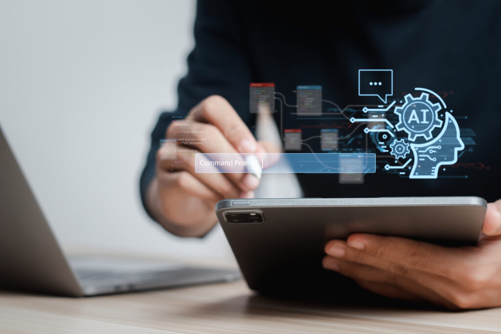 A close up of man's hand as we works on a tablet computer with a stylus. An illustration of a a head and a gear with the initials AI centered hovers superimposed above his tablet. How to budget for AI innovation?
