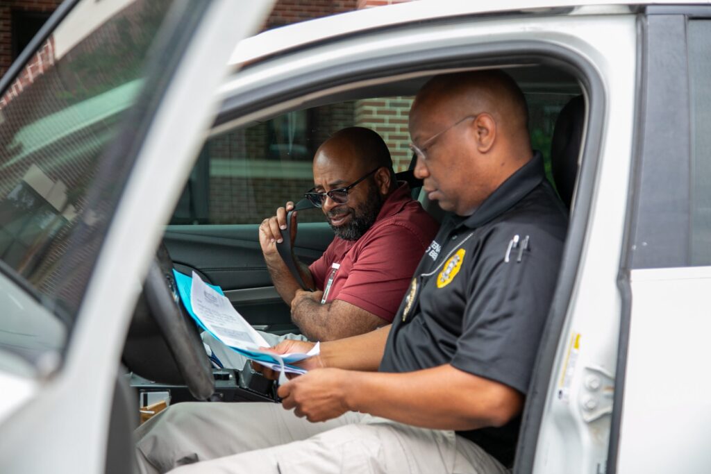 Two police officers going over paperwork in a car