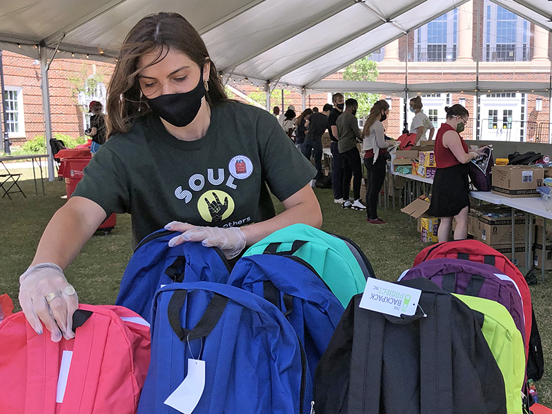 Masked woman picking up backpack