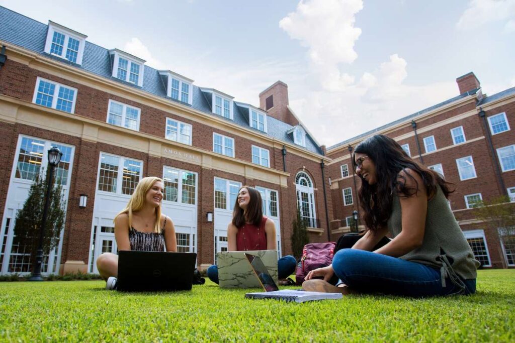 Happy women sitting outside with laptops
