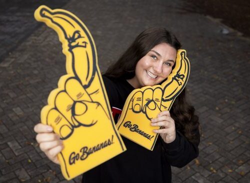 Maren Finnegan a young woman poses with two Savannah Bananas foam fingers.
