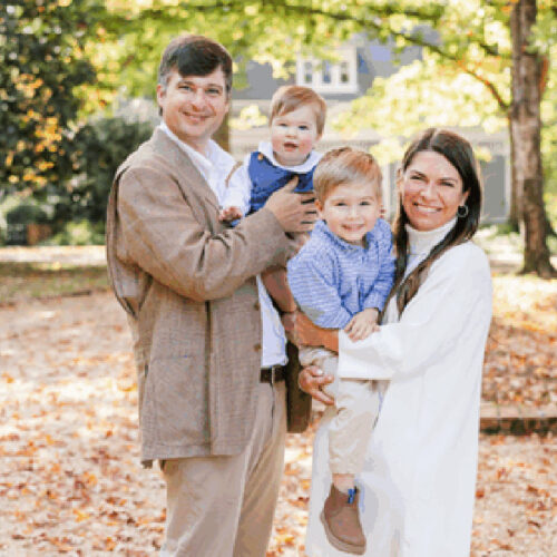 Matt (BBA ’09, MACC ’11) and Adrianne (BBA ’10, MACC ’11) Beacham pose holding their two small children.