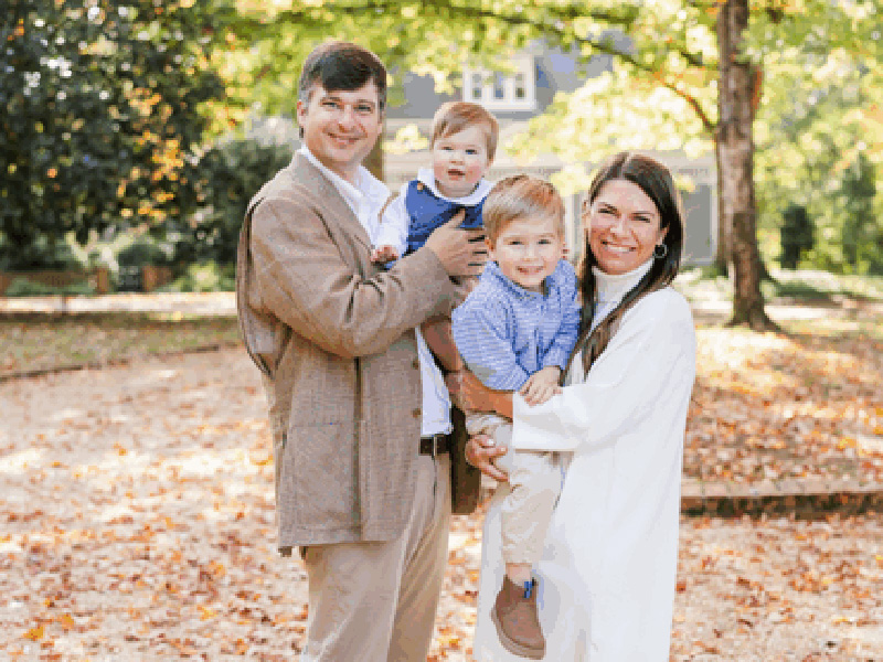 Matt (BBA ’09, MACC ’11) and Adrianne (BBA ’10, MACC ’11) Beacham pose holding their two small children.