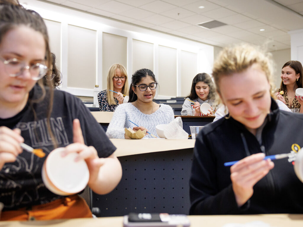 Women in Business members paint bowls in Terry College Classroom