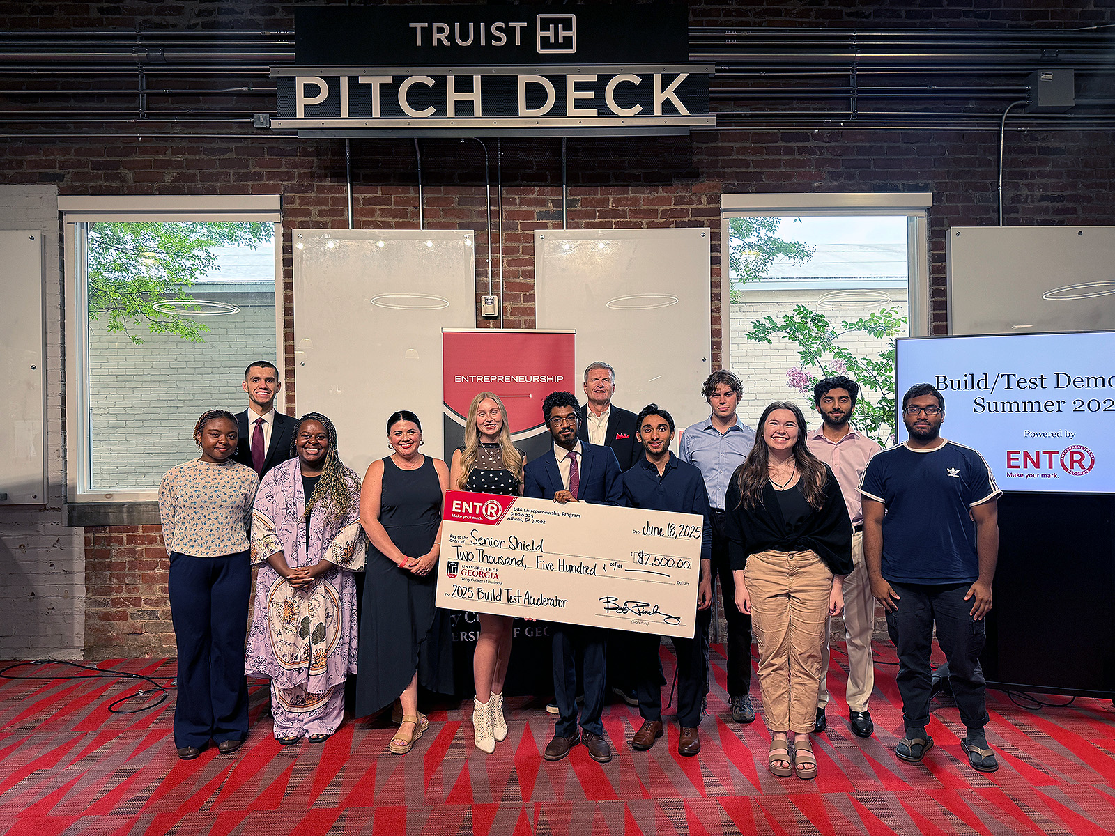 Students and judges at the UGA Entrepreneurship 2025 Build/Test Accelerator Pitch Contest stand in front of the Truist pitch deck.