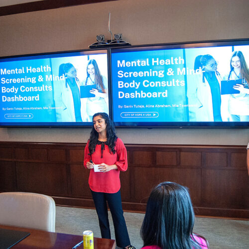 Three UGA students present in a board room in front of slides that read "Mental Health Screening and Mind-Body Consults Dashboards" data-driven health support