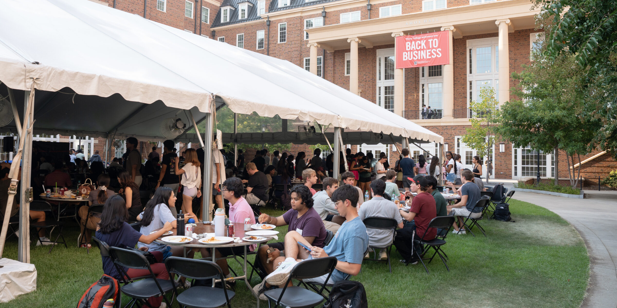 Students spill out a tent on CocaCola plaza at the Business Learning Community Terry College Welcome Back Block Party