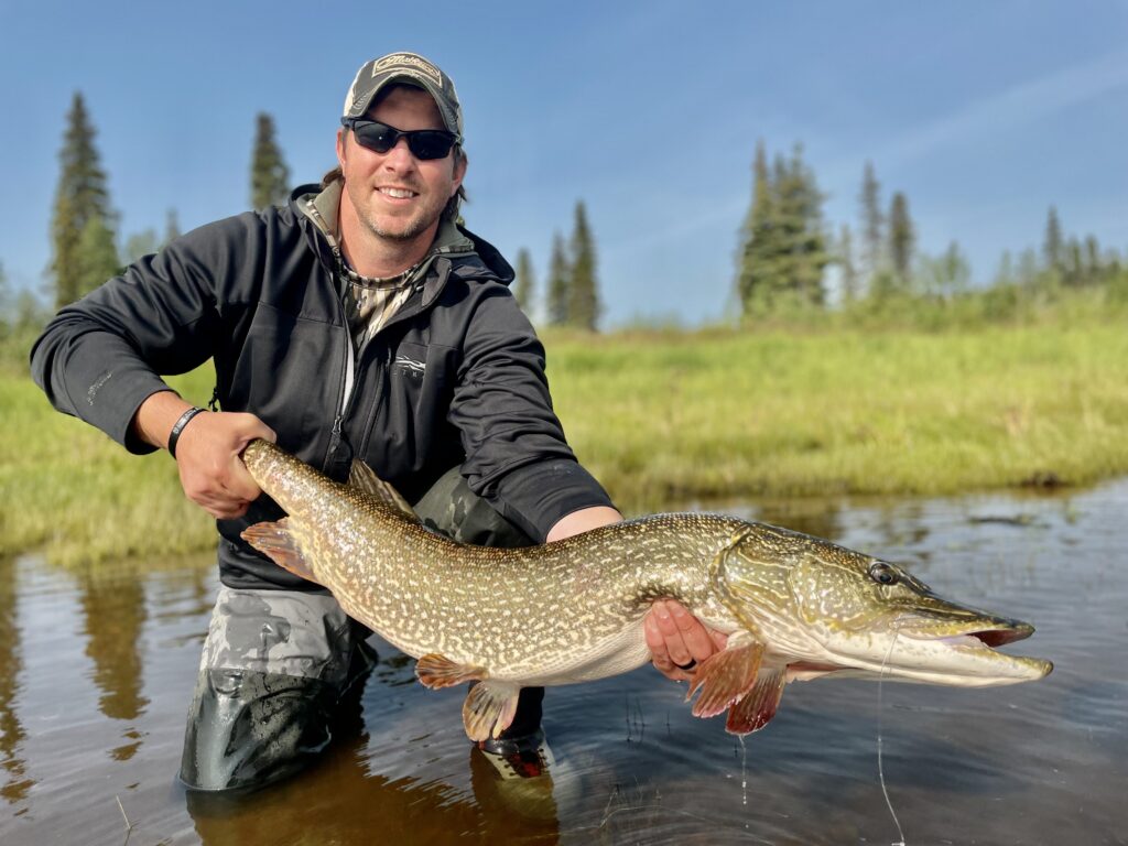 Dallis Joiner poses with a large fish while standing in a river. This Terry PMBA student has startd an Outdoor adventure club Atlanta
