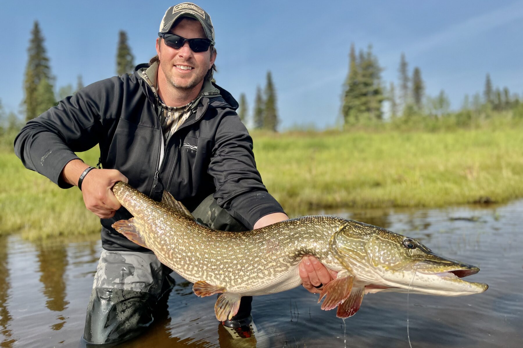 Dallis Joiner poses with a large fish while standing in a river. This Terry PMBA student has startd an Outdoor adventure club Atlanta