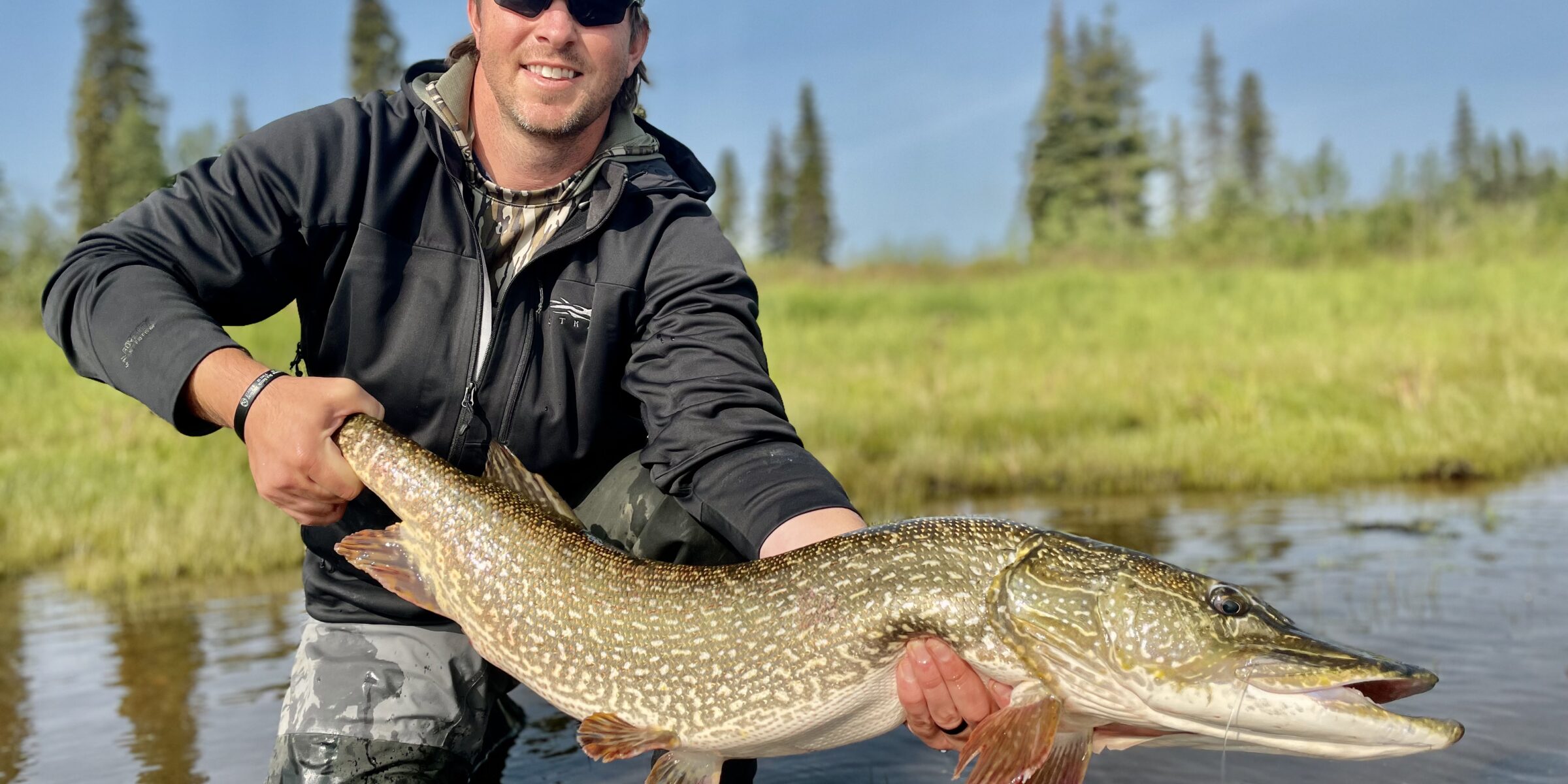 Dallis Joiner poses with a large fish while standing in a river. This Terry PMBA student has startd an Outdoor adventure club Atlanta