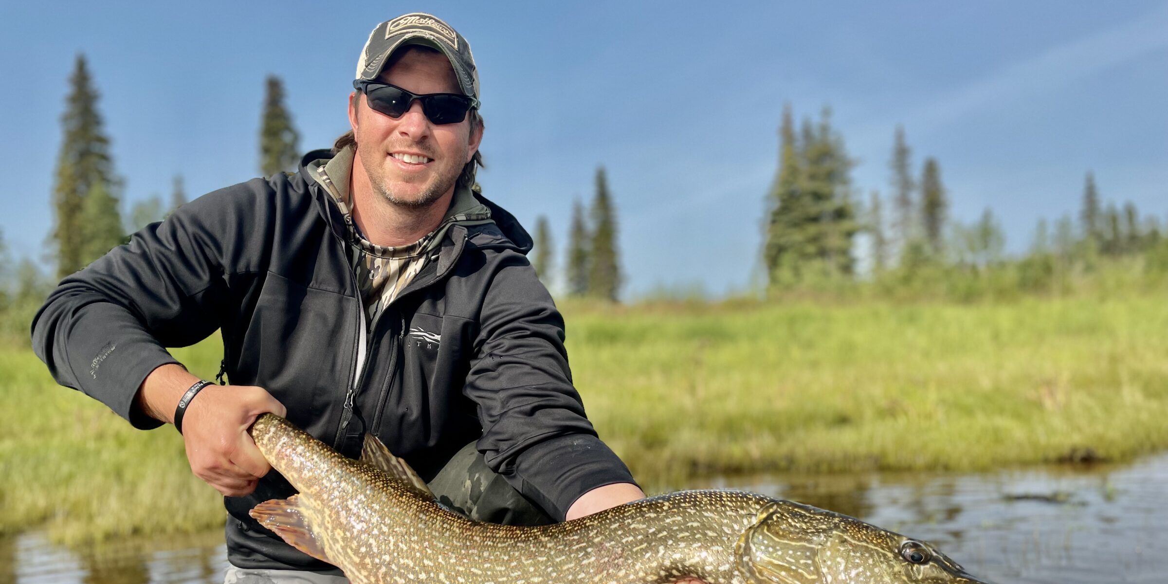 Dallis Joiner poses with a large fish while standing in a river. This Terry PMBA student has startd an Outdoor adventure club Atlanta