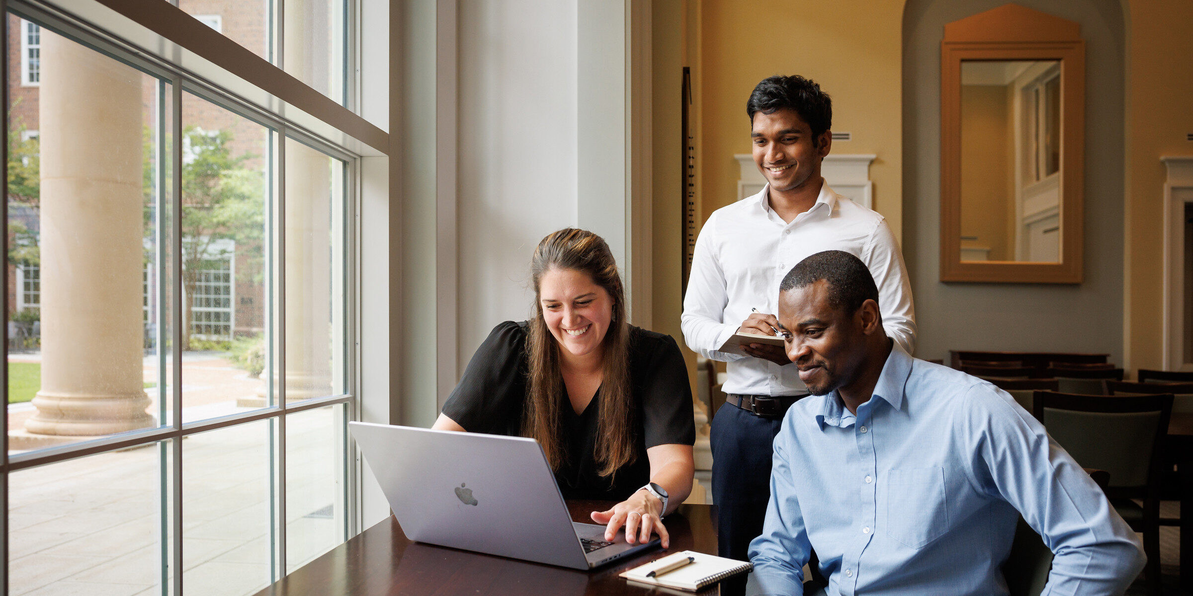 3 people gathered around a laptop