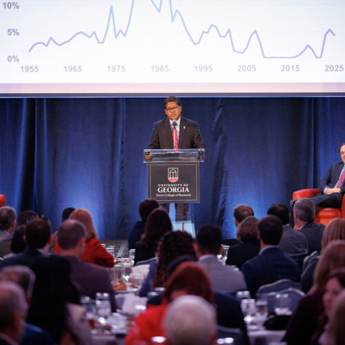 Terry College Interim Dean Santanu Chatterjee delivers the state economic forecast at the UGA's 2026 Economic Outlook in front of large screen showing an economic graph.