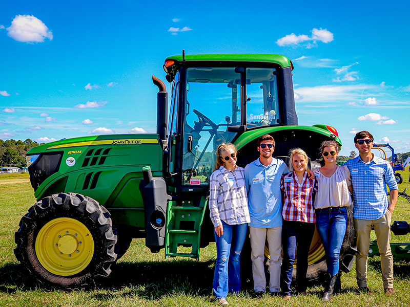 Terry College Students standing in front of a tractor