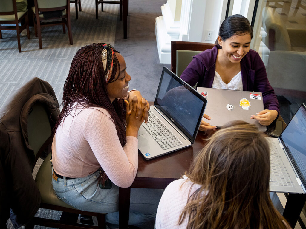 Three female MBA students working on their laptops