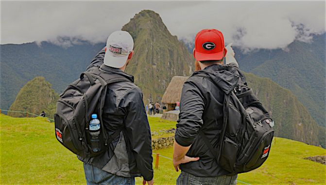 Two hikers wearing University of Georgia hats take in the scenery from a mountaintop.
